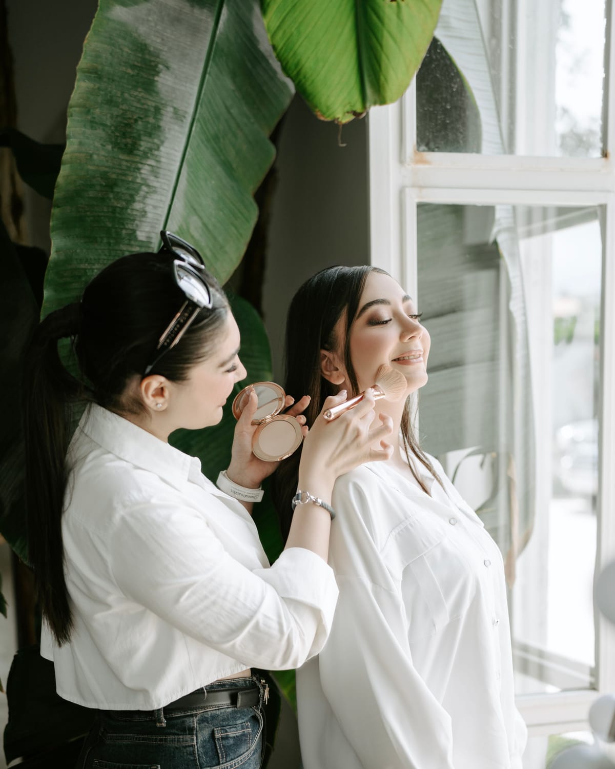 Makeup artist applying a soft base in natural window light