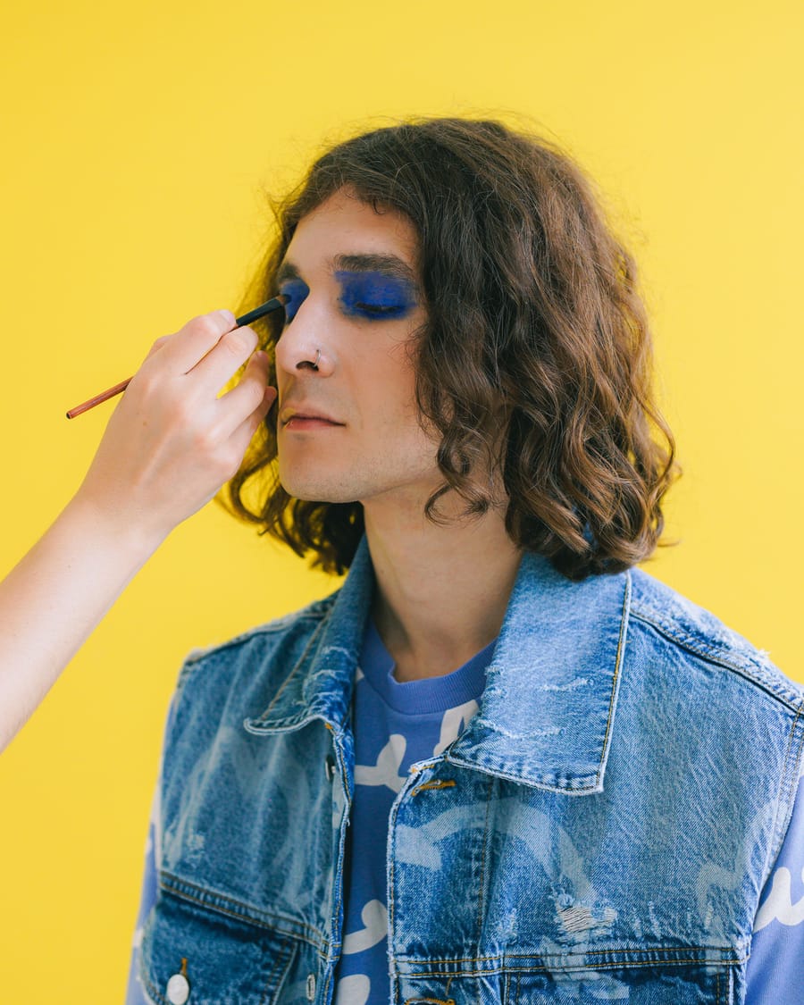 Bold editorial eye makeup in blue against a yellow backdrop