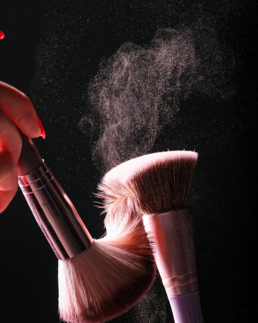 Powder brush caught mid motion against a dark background